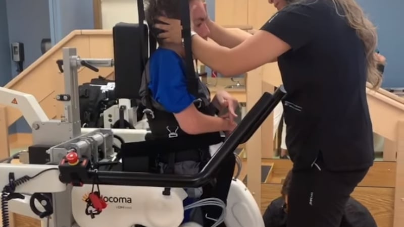 A health care professional helps Luke Siegel use the newly-introduced Lokomat Pro robotic...