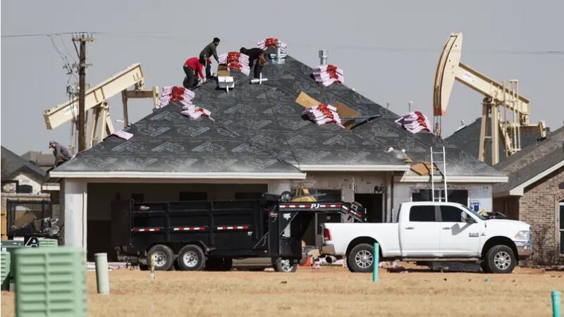 A roofing crew begins to shingle a home under construction in the Pavilion Park development in...